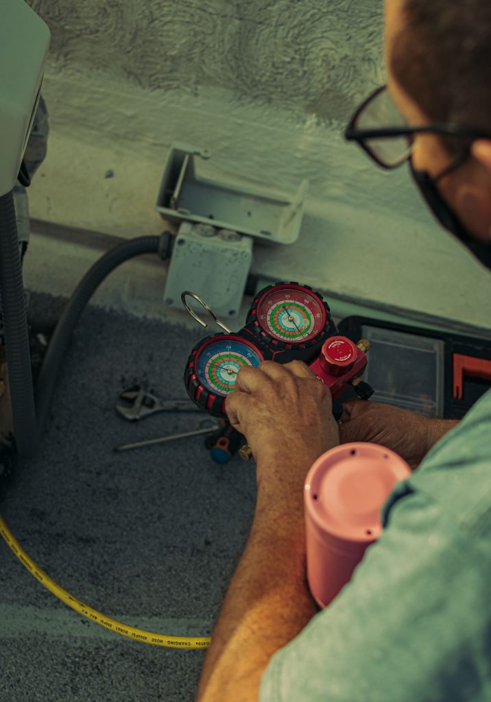 Technician connecting gauges to an air conditioner during a repair