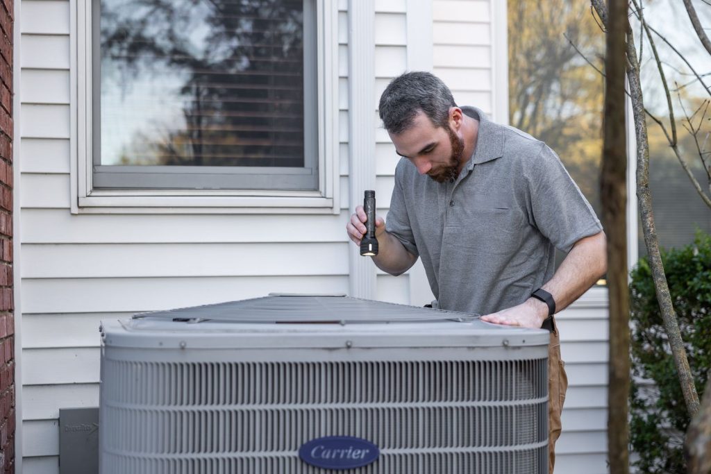 Technician inspecting a residential outdoor AC unit